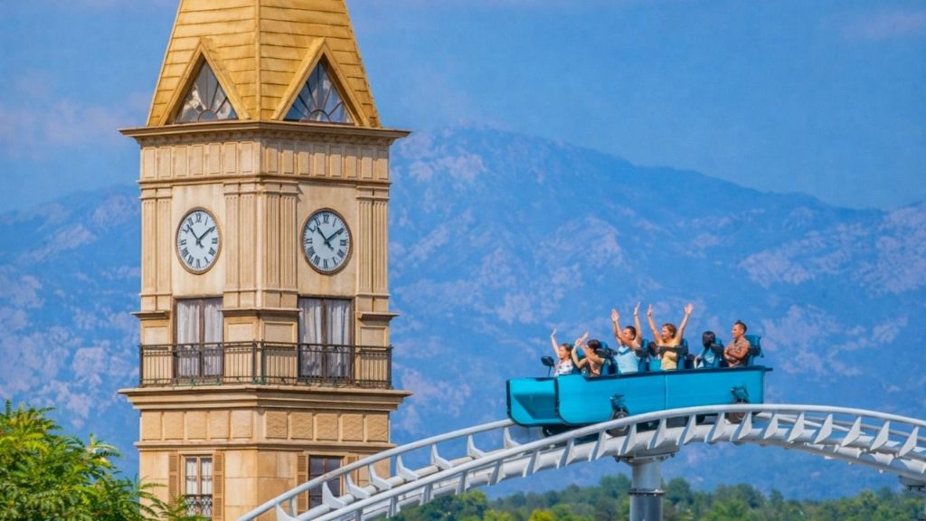 Roller coaster ride next to the clock tower at Land of Legends with Taurus mountains behind
