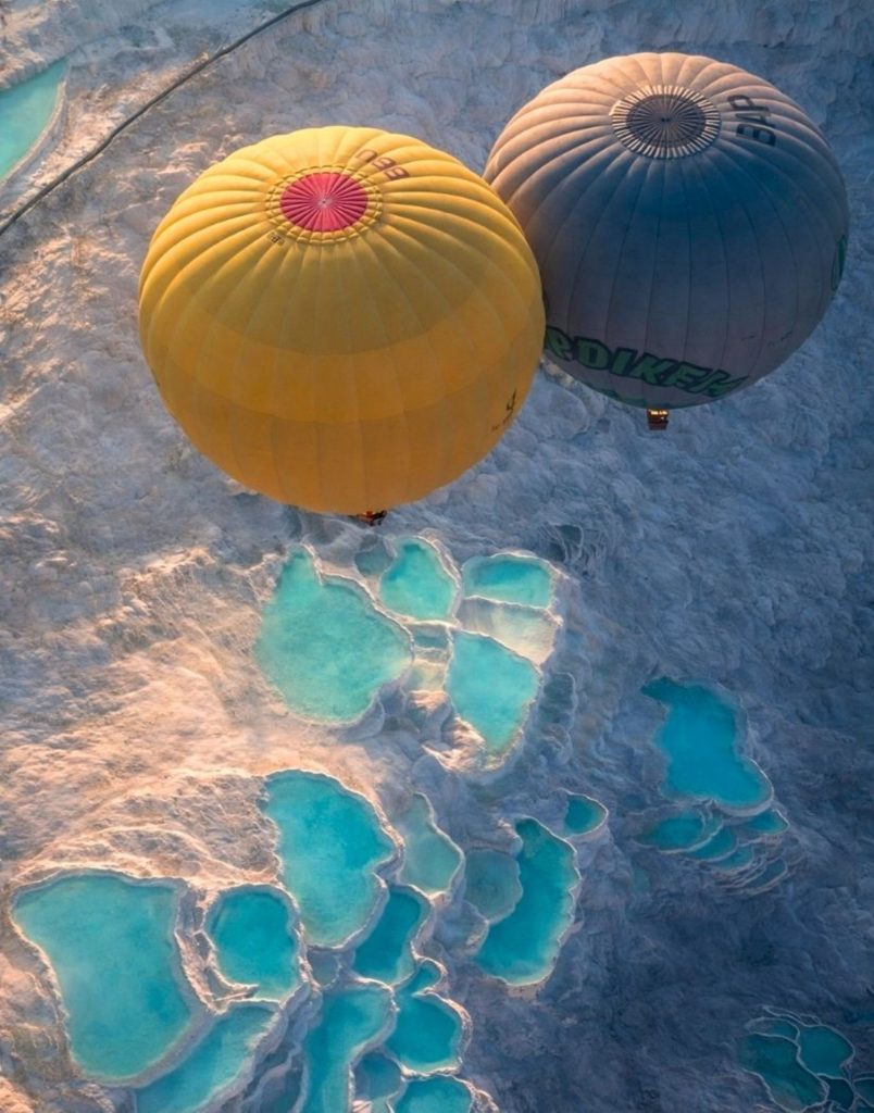 Aerial view of hot air balloons over Pamukkale travertines and thermal pools from above
