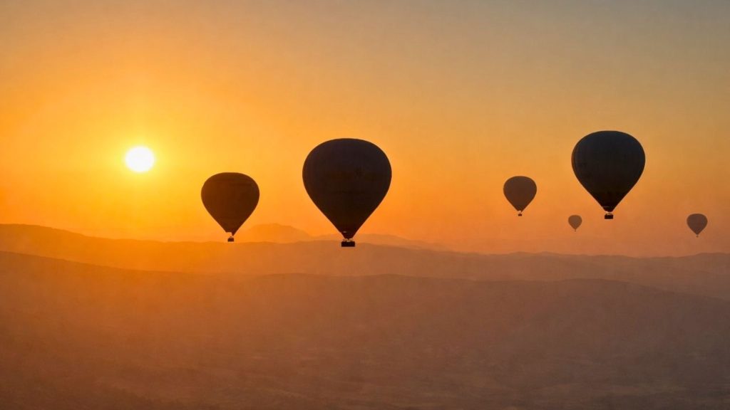 Hot air balloon silhouettes at golden sunrise over Pamukkale mountains during Antalya balloon tour