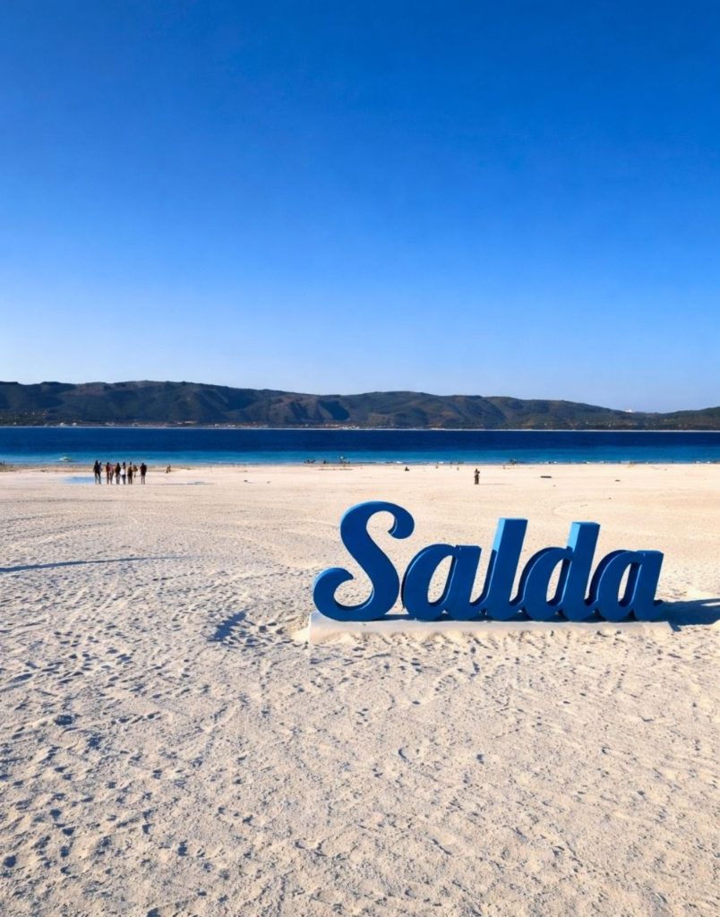 Famous Salda sign on white sand beach of Lake Salda during Antalya Lake Salda and Pamukkale Tour