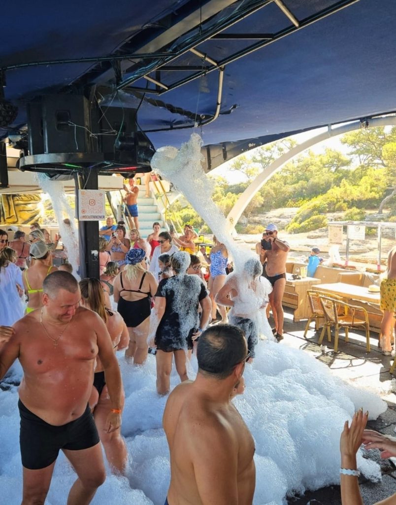 Mega Star boat trip foam party in the sun with pine covered bay in background