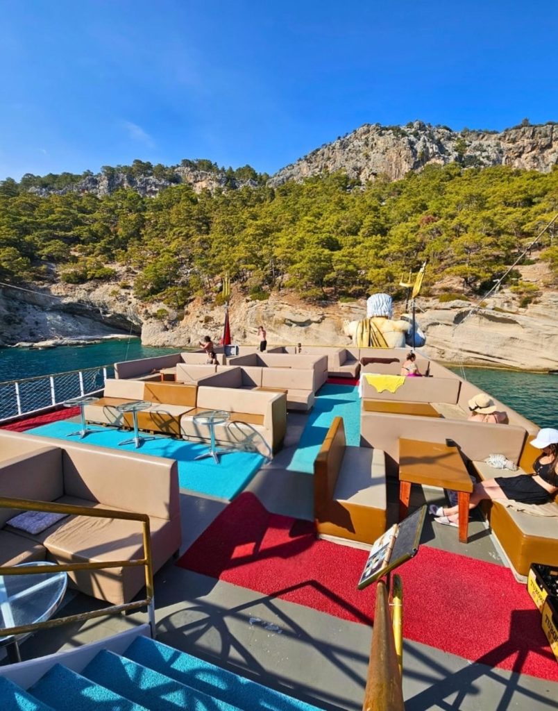 Mega Star boat trip upper deck lounge area with rocky bay and pine trees Kemer coast