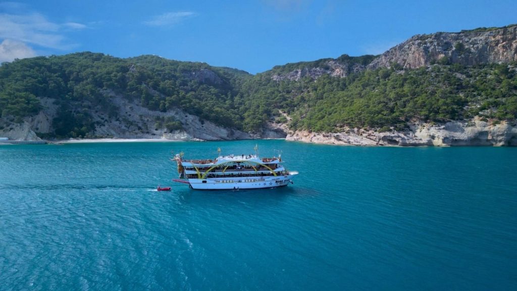 Mega Star cruise boat anchored in turquoise bay with green mountains Kemer coast