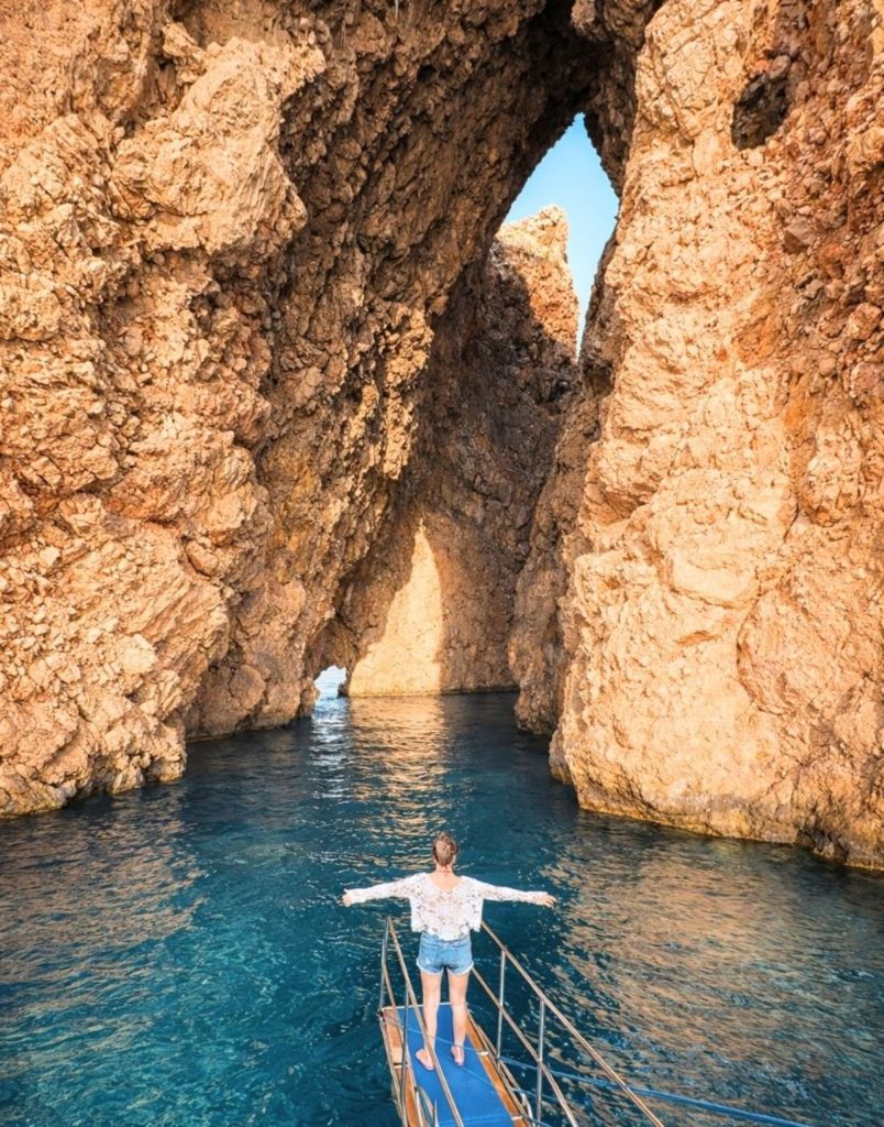 belek suluada boat tour passing through a natural rock arch formation over turquoise water