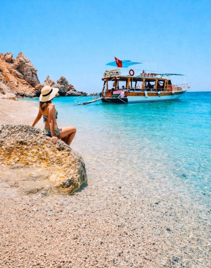 belek suluada boat tour with wooden boat anchored in crystal clear shallow water near rocky shore