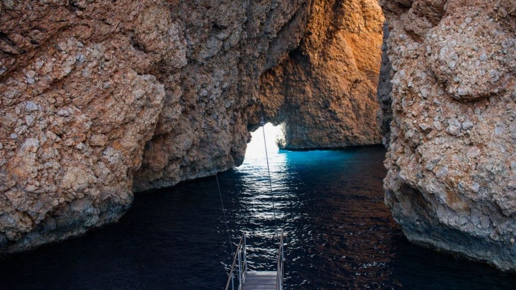 belek suluada boat tour entering a sea cave with turquoise light and rocky walls
