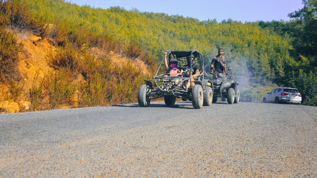 Buggy and quad driving on scenic mountain road with green hills in Alanya