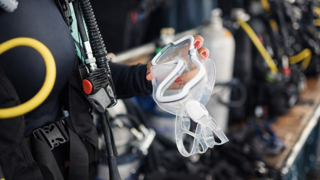 Diver in wetsuit holding professional diving mask on Alanya diving tour boat