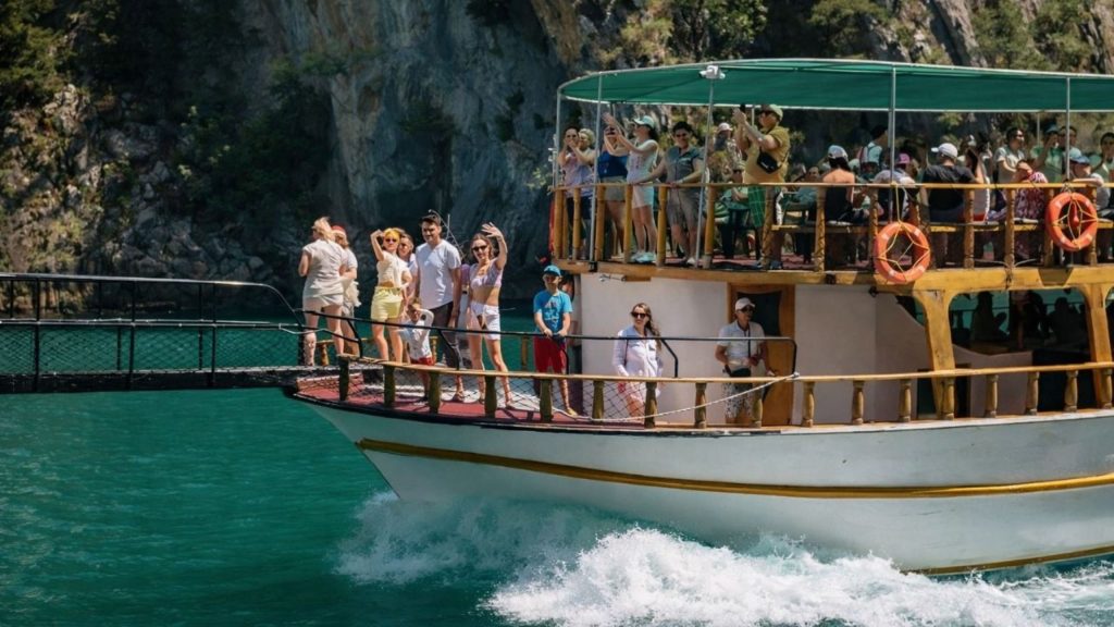 Tour boat full of happy visitors waving on Green Canyon boat trip from Alanya