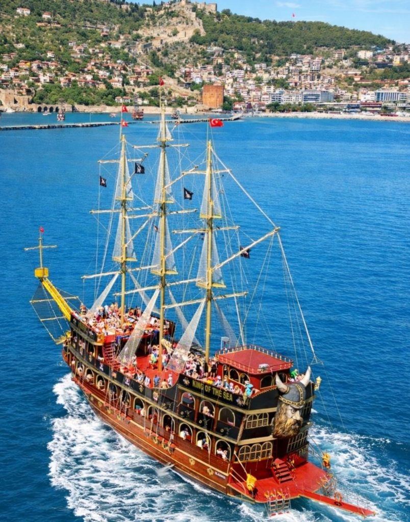 King of the Sea pirate boat sailing past Alanya Castle and Red Tower
