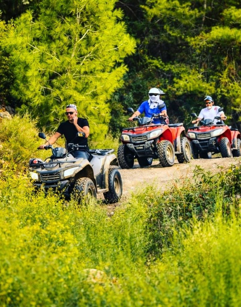 Three quad bikes riding through lush green forest trail in Alanya mountains