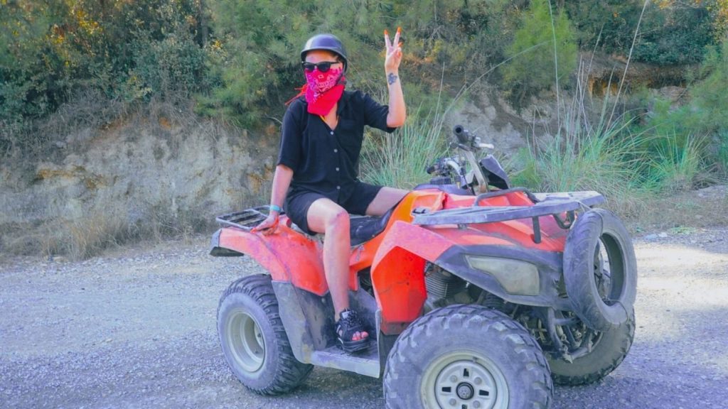 Quad bike rider with helmet and bandana on dirt road in Alanya forest