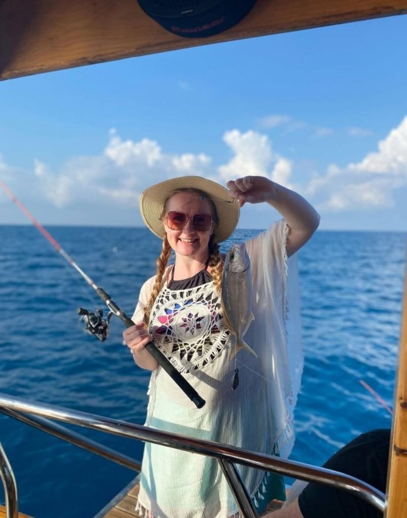 Smiling woman holding her fish catch on the Alanya fishing tour boat