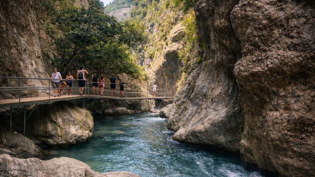 Walking bridge over turquoise river between tall rock walls inside Sapadere Canyon