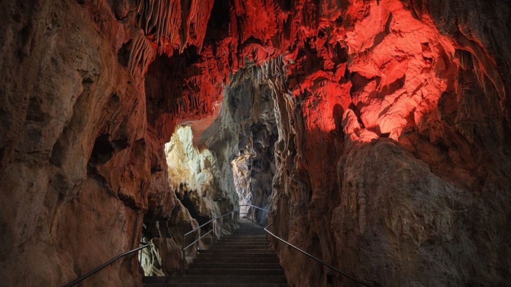 Red-lit cave with stalactites and stone stairway at Dim Cave near Alanya