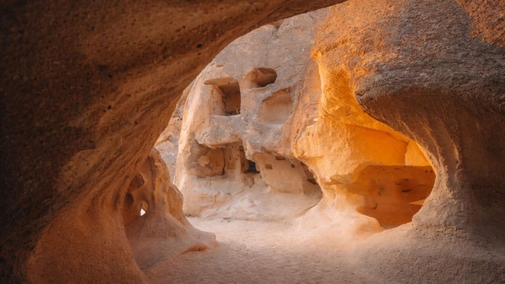 Ancient cave dwellings carved into rock with warm golden light in Cappadocia