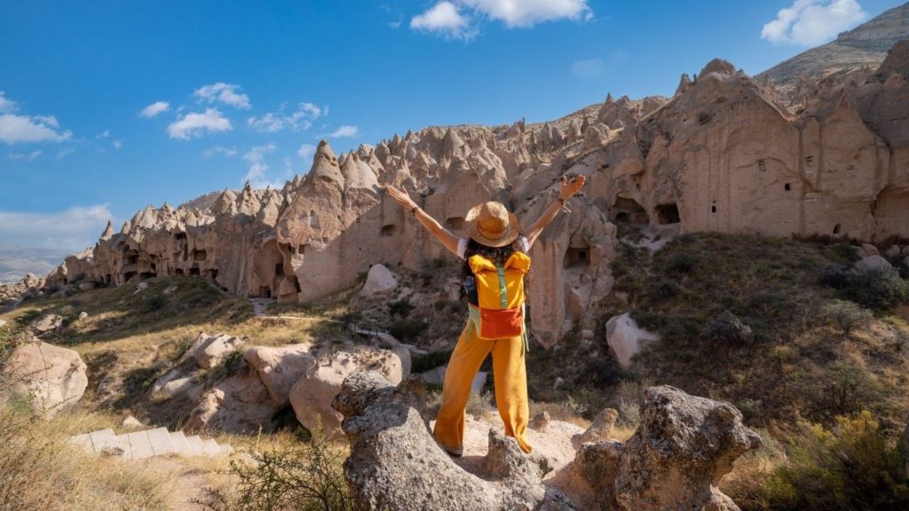 Traveller with arms open in front of Cappadocia fairy chimneys and cave houses