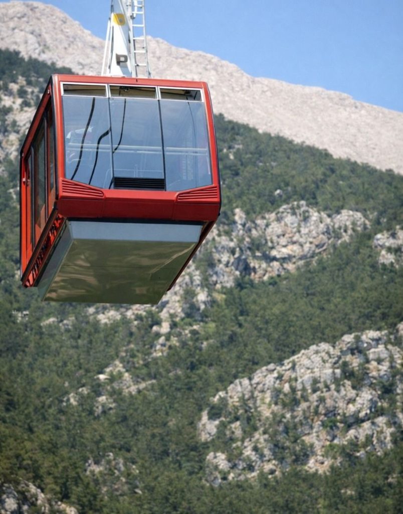 olympos cable car red gondola close up with forested mountain slope in the background