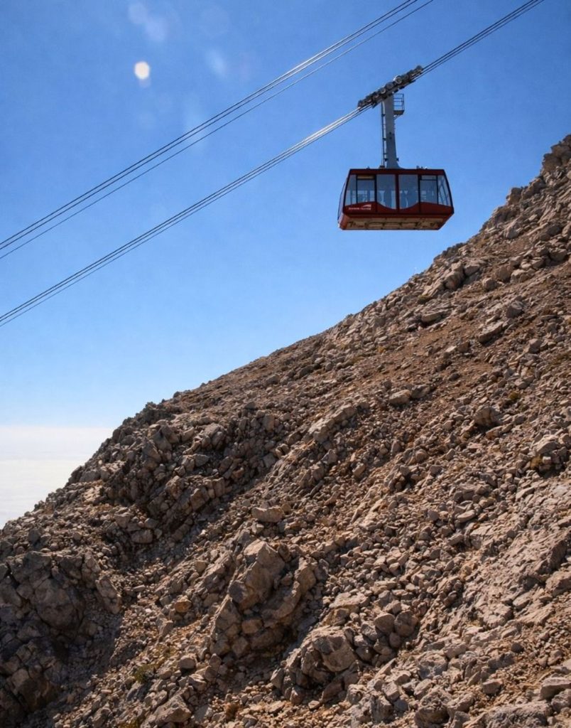 olympos cable car gondola approaching the barren rocky tahtali summit under blue sky