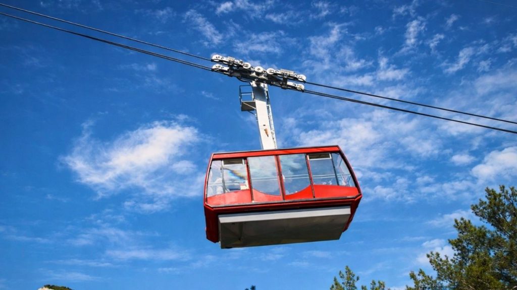 olympos cable car red gondola against blue sky above the pine trees