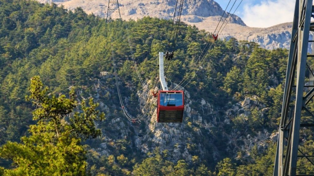 olympos cable car gondola ascending over pine forests toward the rocky tahtali summit