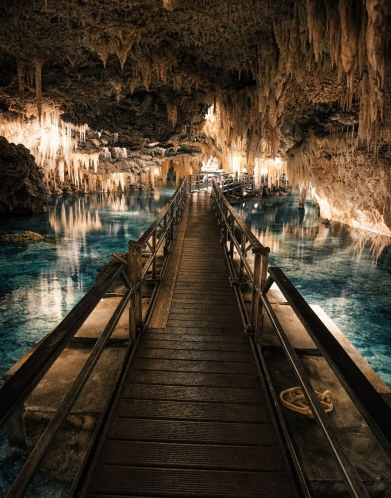 Walkway over crystal-clear underground lake inside Altinbesik Cave with stalactites on Alanya cave tour
