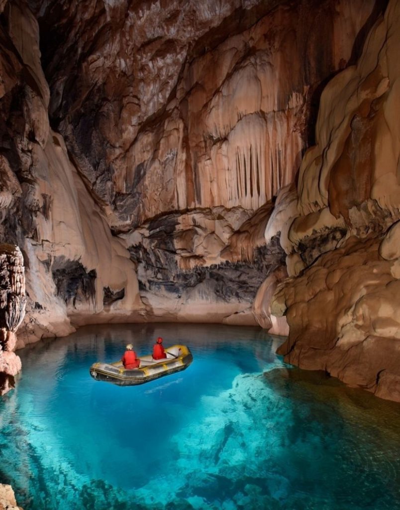 Boat trip through turquoise underground river inside illuminated Altinbesik Cave near Alanya