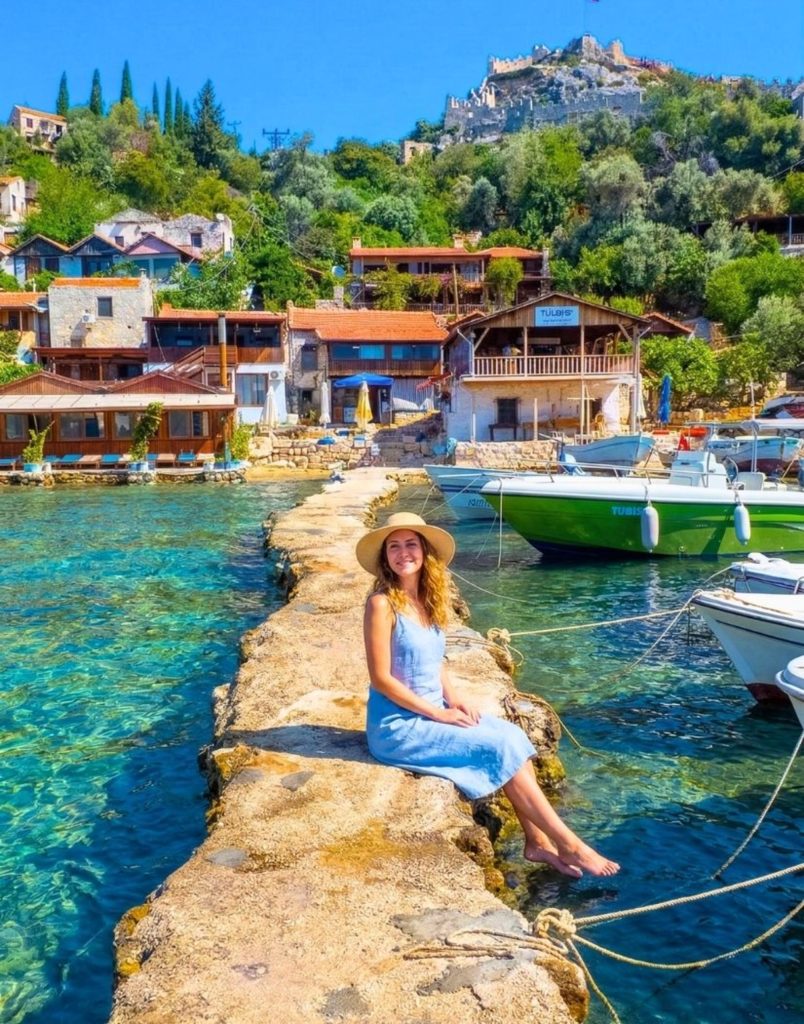 Visitor sitting on pier at charming Kekova village with turquoise water on Demre Myra Kekova tour