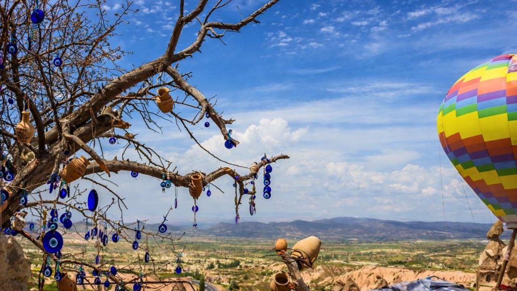 Cappadocia evil eye tree with hot air balloon and valley panorama in background