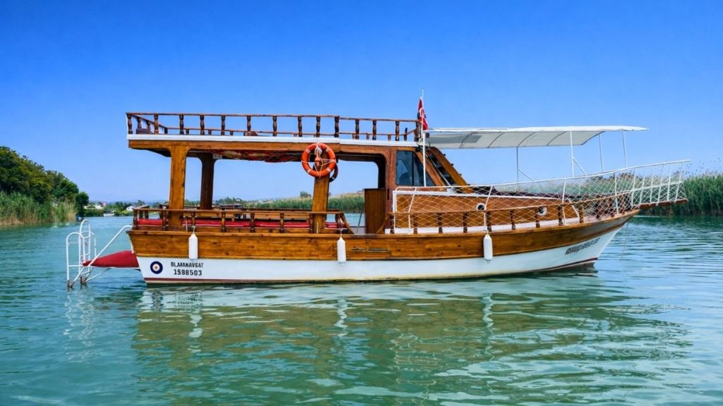 traditional wooden manavgat fishing boat on calm green river near side