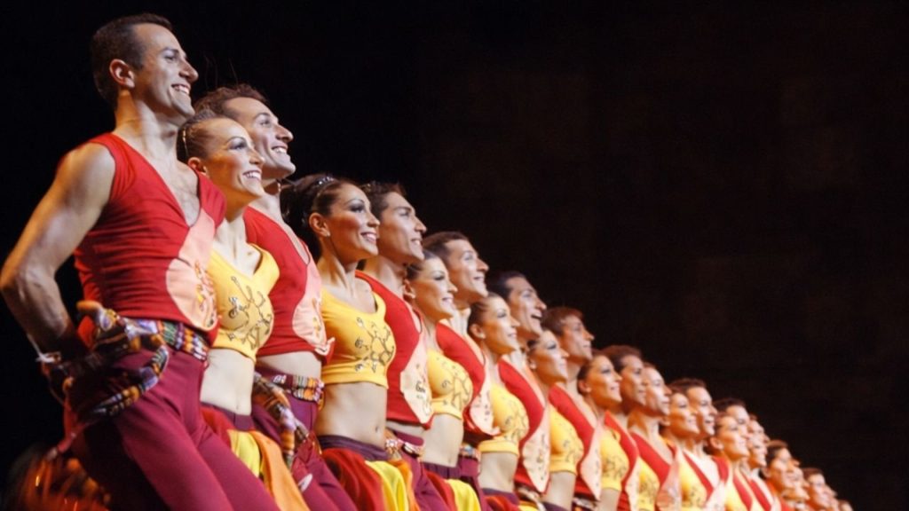 Row of dancers in colourful red yellow traditional costumes at Fire of Anatolia show