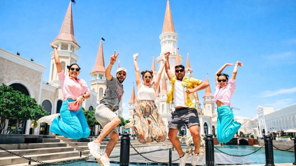 Excited group jumping in front of iconic Land of Legends castle entrance in Antalya