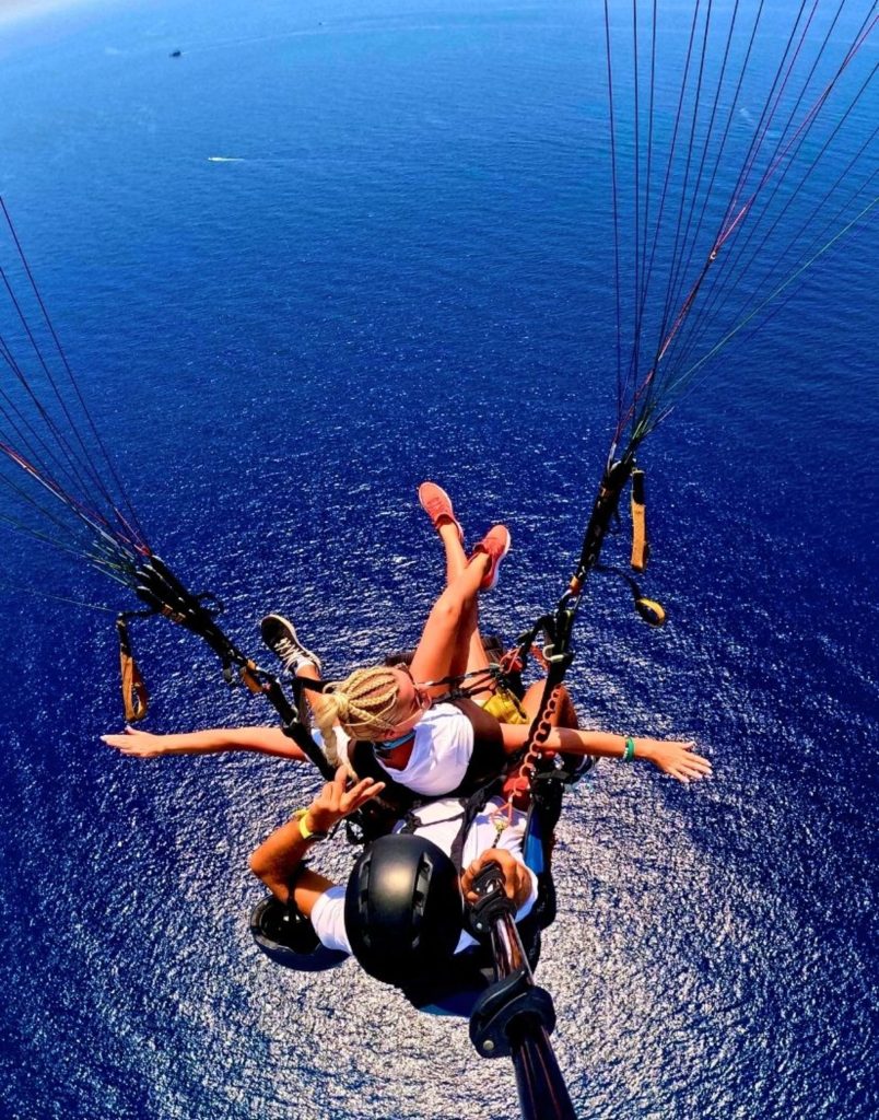 Tandem paragliding flight with arms spread wide over open Mediterranean sea in Antalya