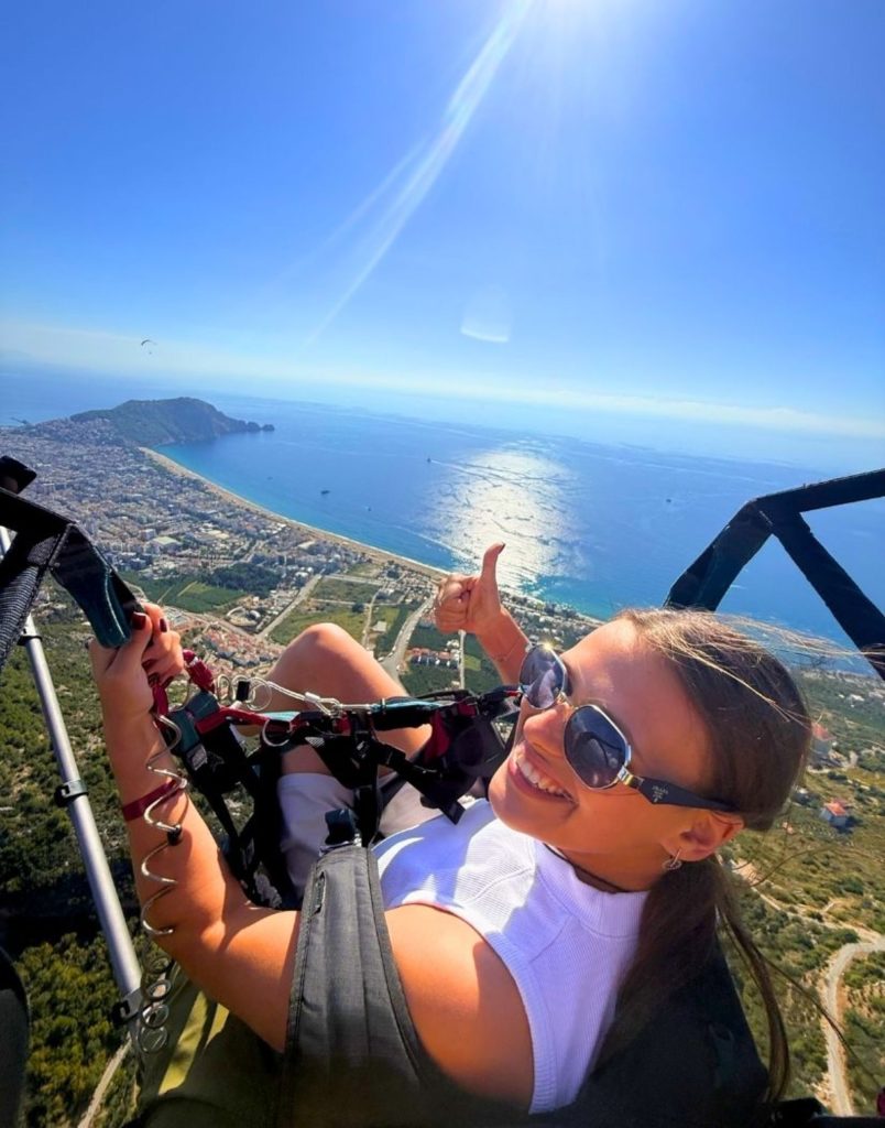 Happy paragliding selfie with Antalya coastline mountains and sparkling sea below
