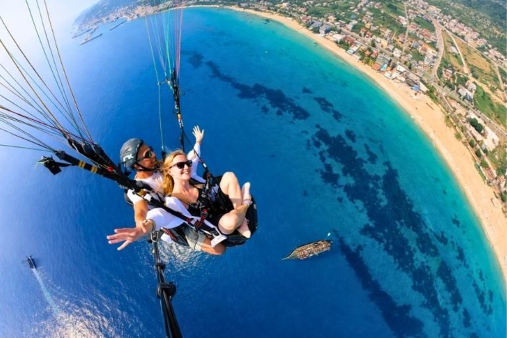 Tandem paragliding flight over Antalya coastline and turquoise Mediterranean sea