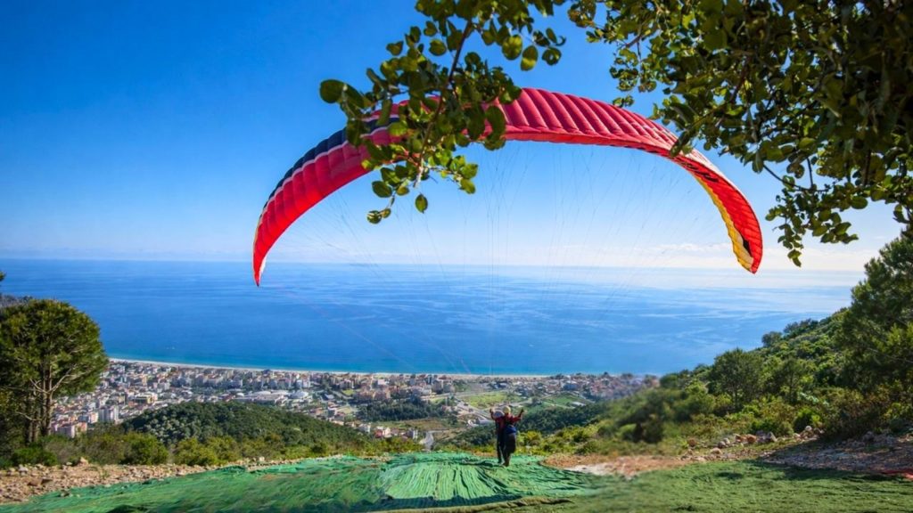 Paraglider launching from mountain takeoff point with Antalya coastline and sea view