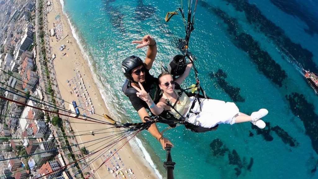Tandem paragliding selfie flying over Antalya beach and turquoise Mediterranean sea