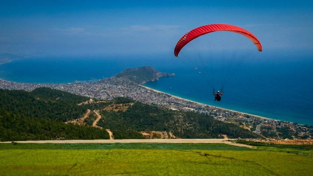 Paraglider soaring over Antalya city coastline and Mediterranean sea from mountain launch site