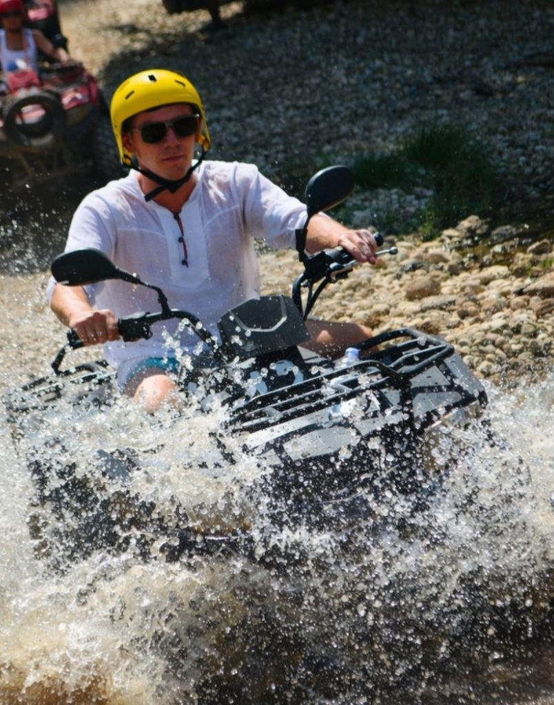 Quad bike blasting through river water with big splash on Antalya off-road safari