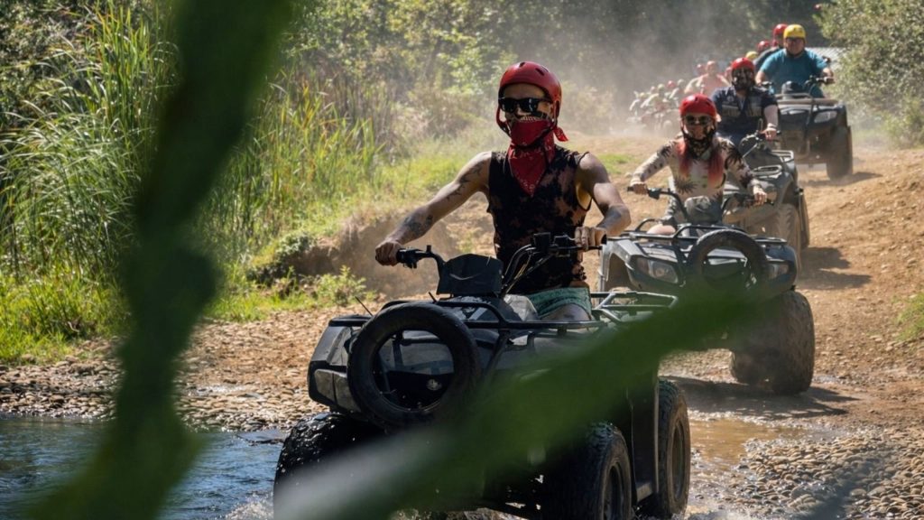 Quad bike convoy splashing through river crossing on dusty off-road trail in Antalya