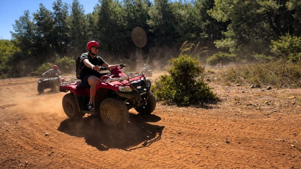 Quad bike racing through red dusty off-road track surrounded by pine forest in Antalya