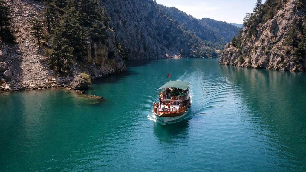 Tour boat cruising through Green Canyon emerald waters surrounded by rocky cliffs Manavgat