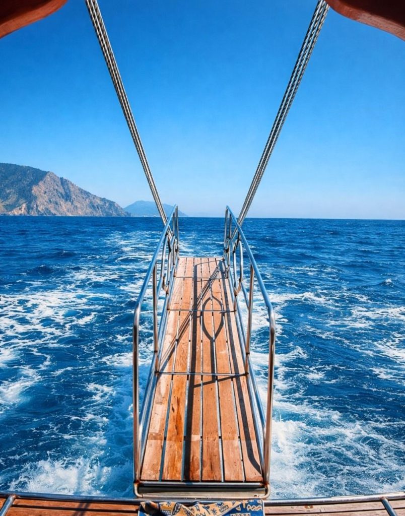 belek suluada boat tour stern gangway view with deep blue sea and mountain silhouette