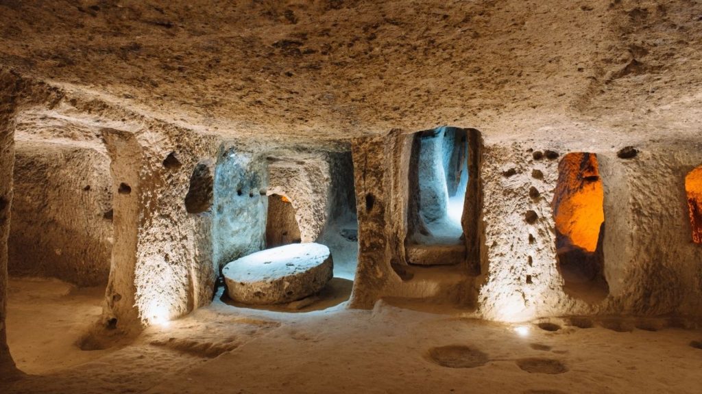 Ancient underground city carved into rock in Cappadocia with stone doors and tunnels