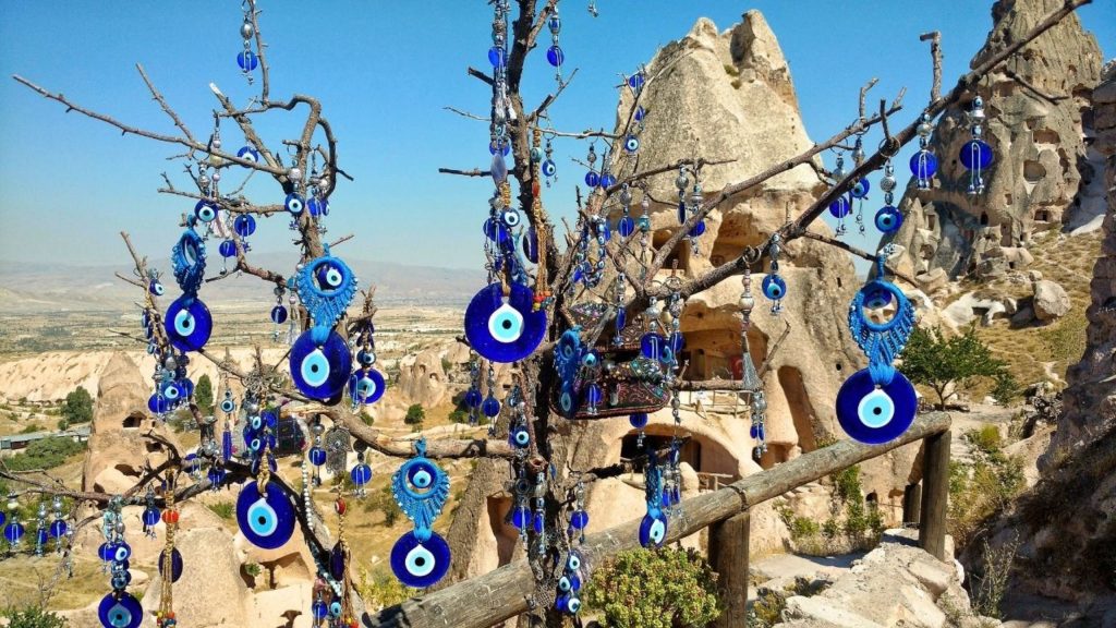Traditional evil eye charms hanging from tree with Cappadocia fairy chimneys in background