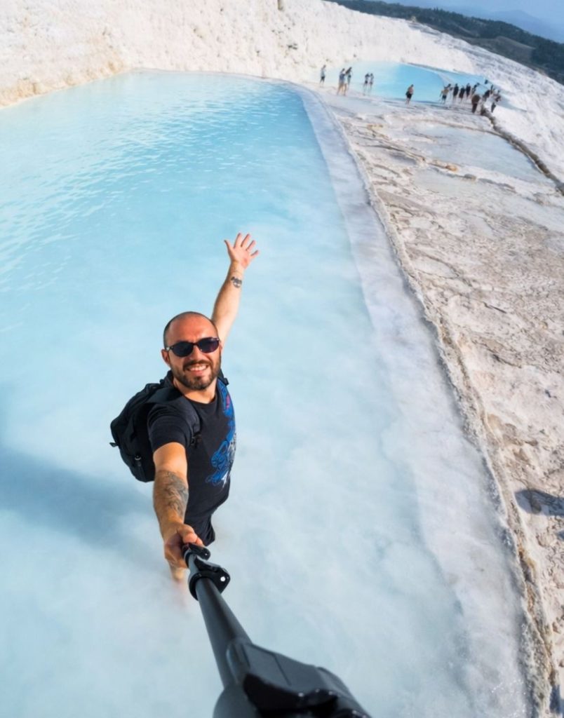 Visitor taking a selfie in Pamukkale travertine thermal pool with turquoise water