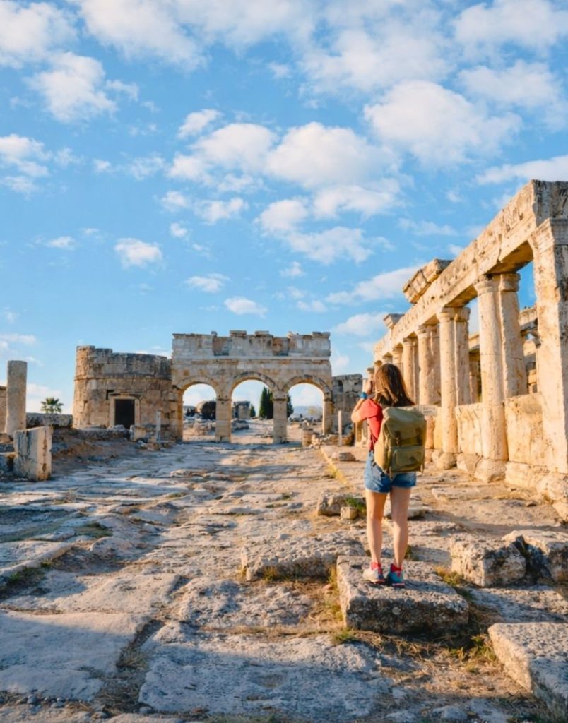 Traveler photographing ancient Hierapolis ruins and Roman columns on a Pamukkale day trip