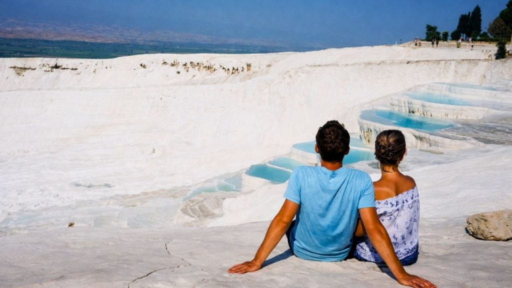 Couple enjoying the view of turquoise thermal pools on Pamukkale white travertine terraces