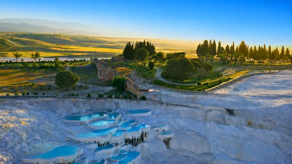 Panoramic sunset view of Pamukkale travertine pools and ancient Hierapolis ruins