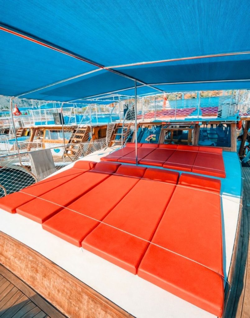Comfortable sun deck with red cushions on Suluada Island tour boat from Antalya
